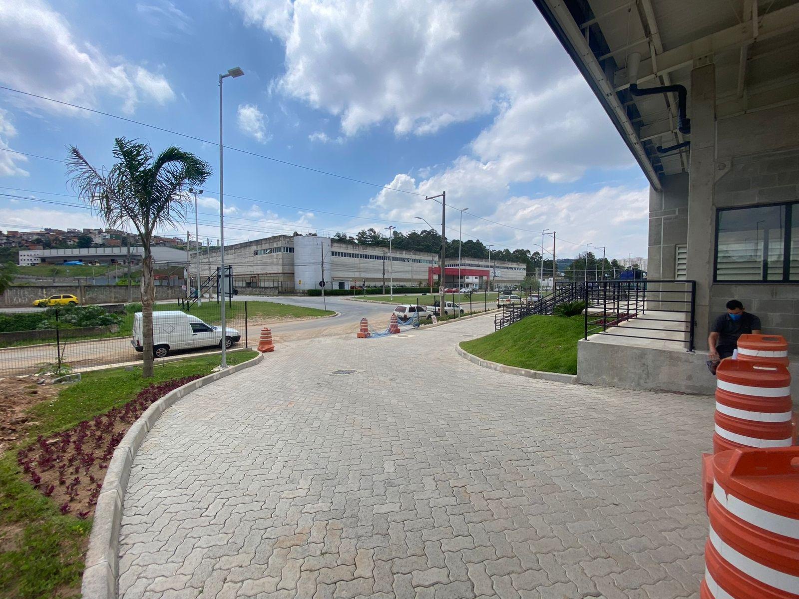 Via de acesso curva com guias e canteiro de flores ao lado de um galpão